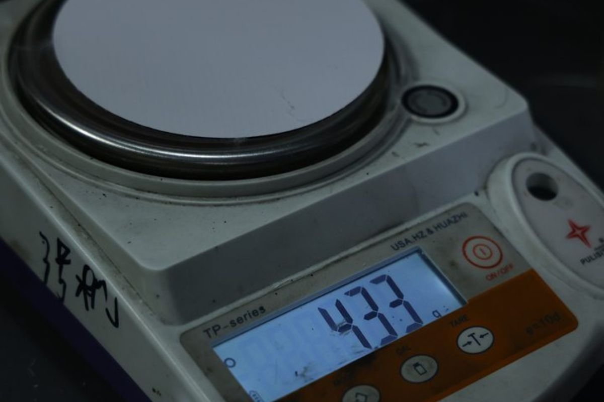 A small sample of banner material on a precision scale, indicating its weight. A sample of banner material placed on a scale