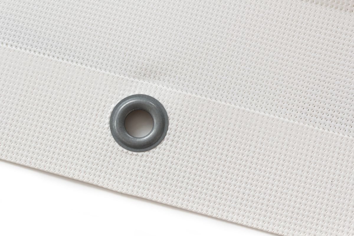 A close-up of a reinforced grommet on an unhemmed mesh banner edge. Reinforced grommet on mesh banner