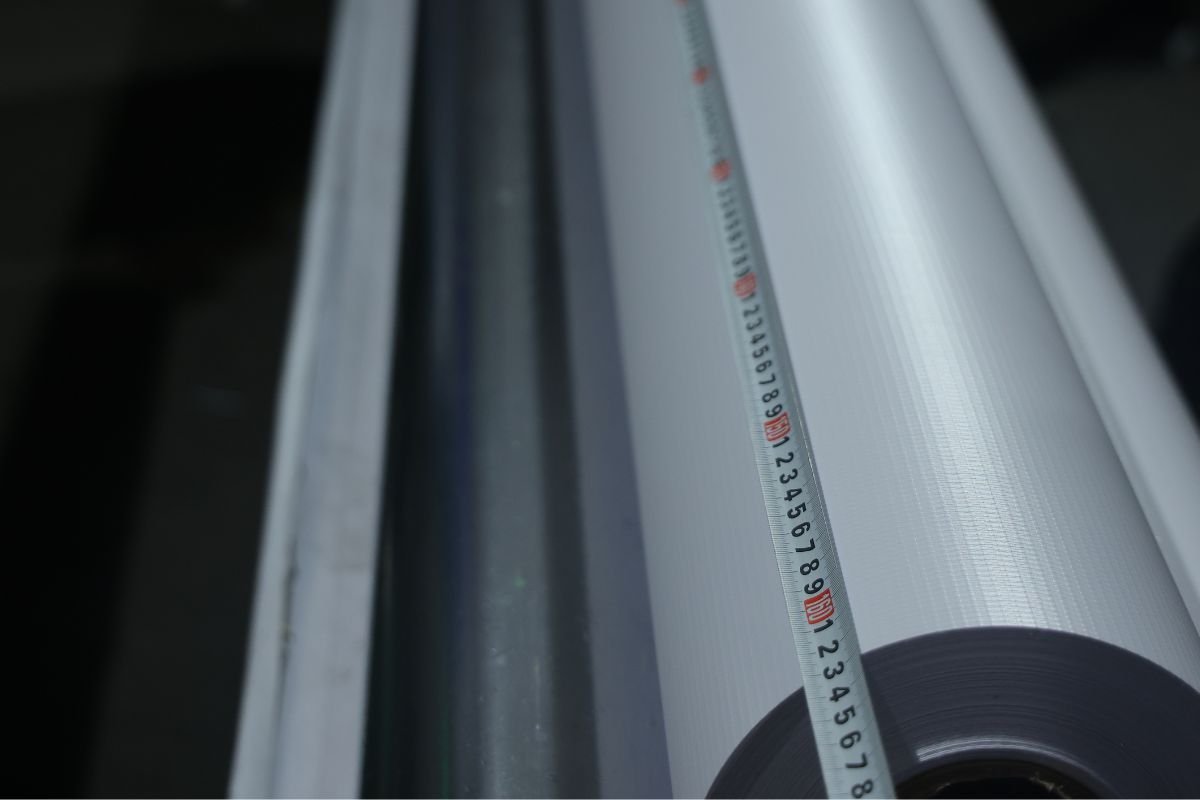 Large rolls of white vinyl banner material ready for printing. Stack of large format vinyl banner rolls